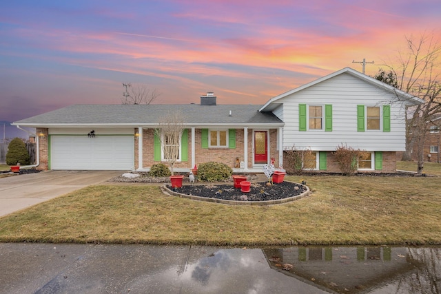 tri-level home with a garage, concrete driveway, and brick siding