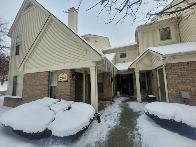 snow covered property with brick siding