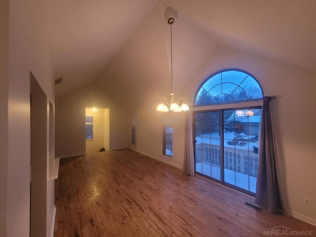 interior space with high vaulted ceiling, wood finished floors, visible vents, and an inviting chandelier