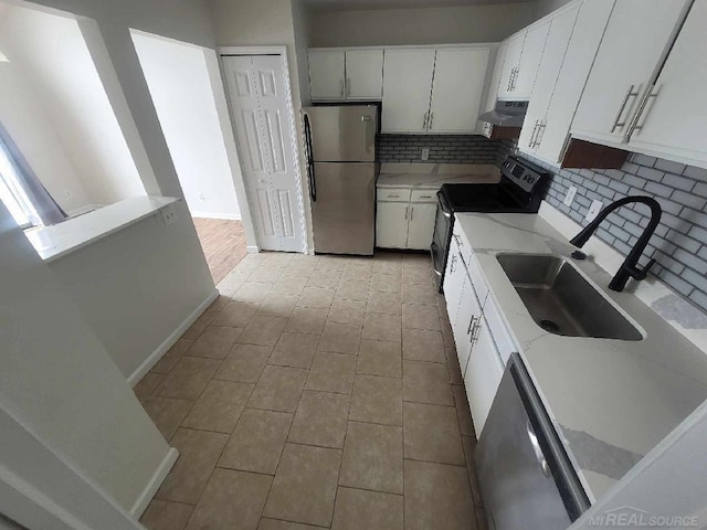 kitchen with decorative backsplash, appliances with stainless steel finishes, white cabinetry, a sink, and exhaust hood