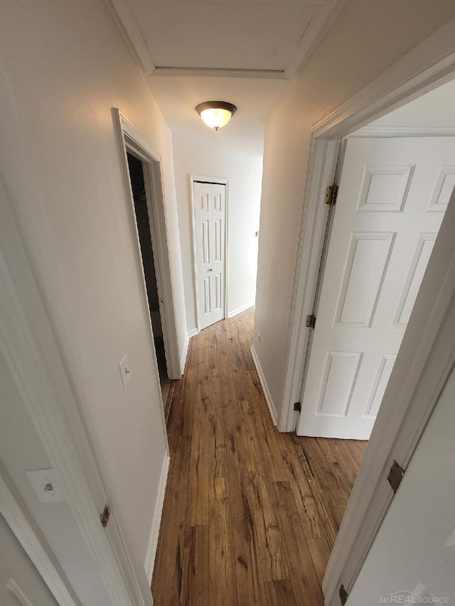 corridor with attic access, baseboards, and wood finished floors