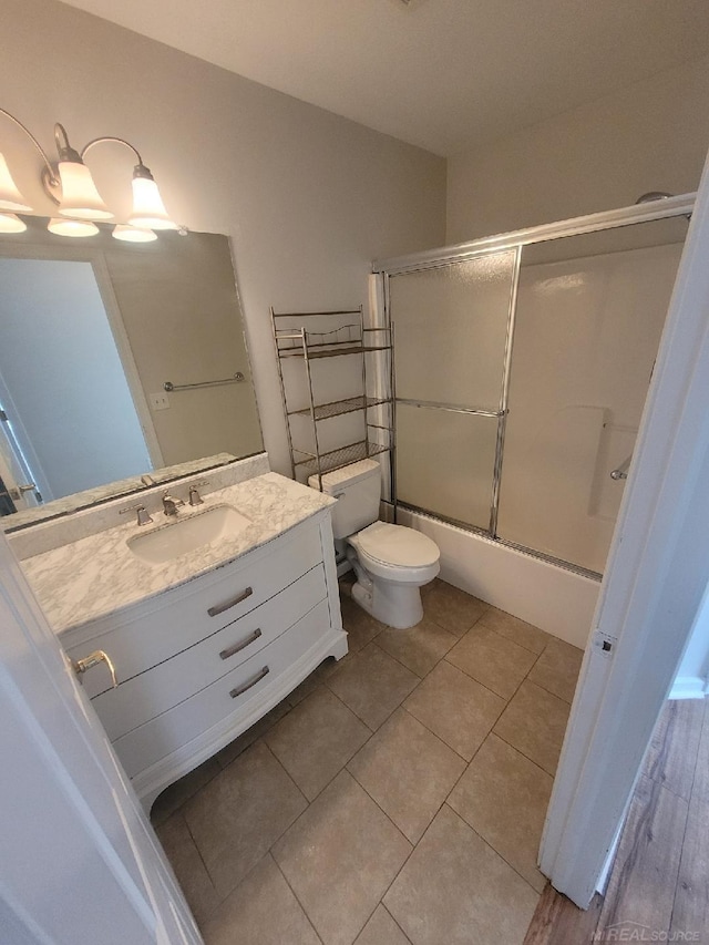 full bath with tile patterned flooring, enclosed tub / shower combo, vanity, and toilet