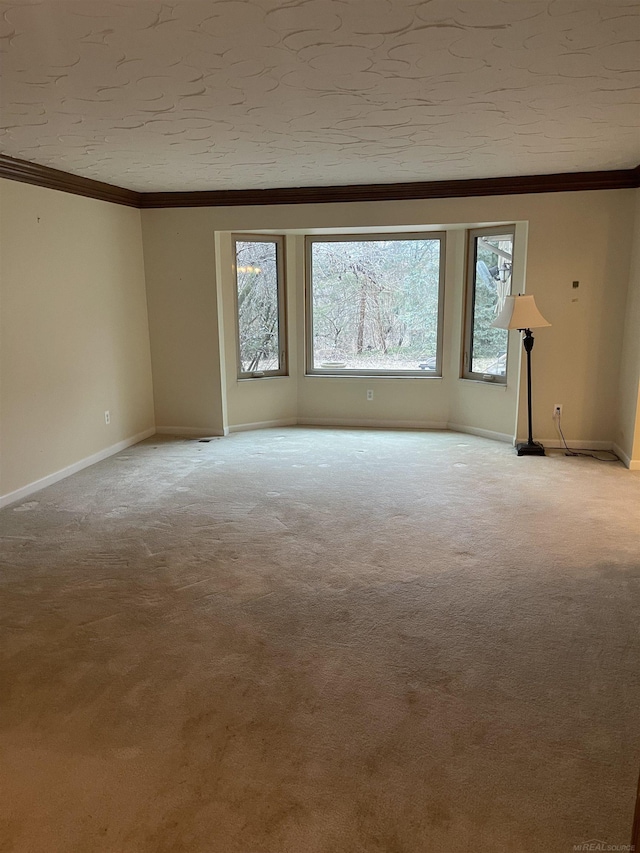 unfurnished room featuring baseboards, a textured ceiling, light colored carpet, and crown molding