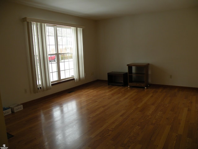 spare room featuring dark wood-type flooring and baseboards