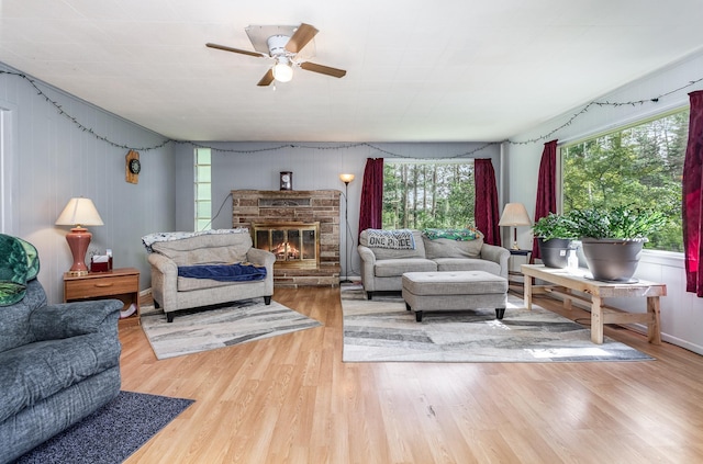 living room with a glass covered fireplace, ceiling fan, and wood finished floors