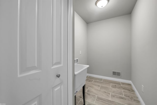 washroom featuring baseboards, visible vents, and wood finish floors