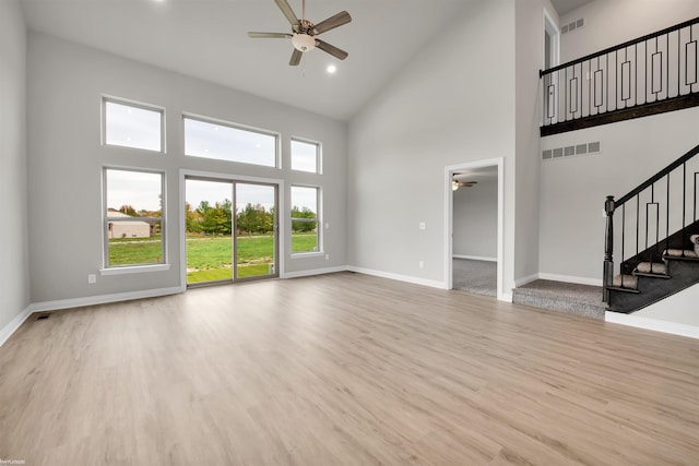 unfurnished living room with visible vents, stairway, baseboards, and wood finished floors