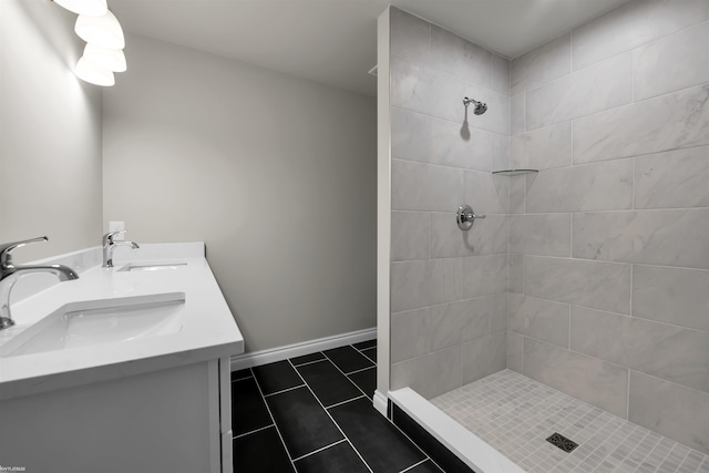 full bath featuring tiled shower, a sink, and baseboards