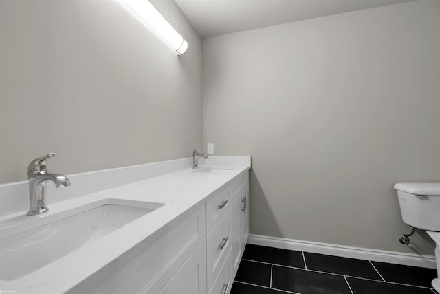 bathroom featuring baseboards, a sink, toilet, and tile patterned floors