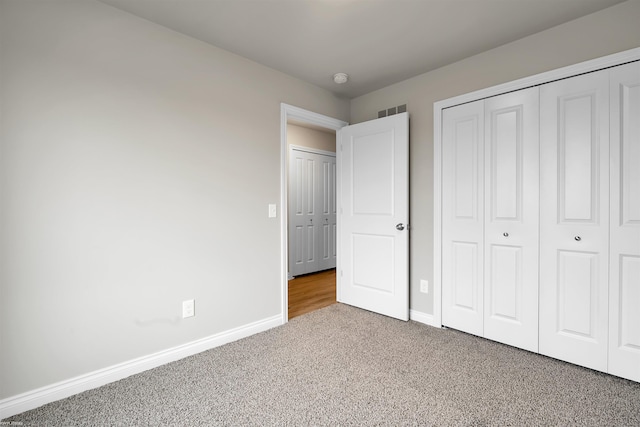 unfurnished bedroom featuring carpet floors, a closet, visible vents, and baseboards