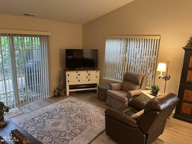 living room with lofted ceiling, wood finished floors, and visible vents