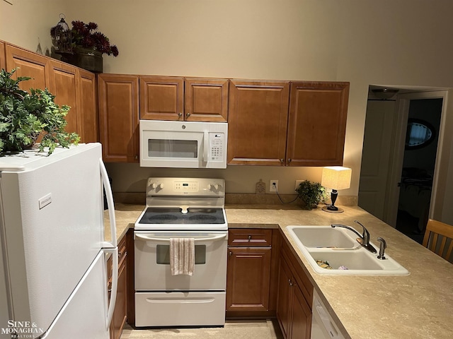 kitchen with brown cabinets, white appliances, light countertops, and a sink