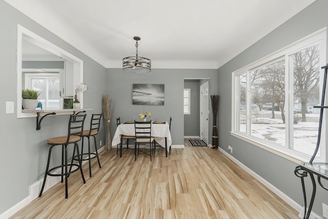 dining room with a notable chandelier, baseboards, and wood finished floors