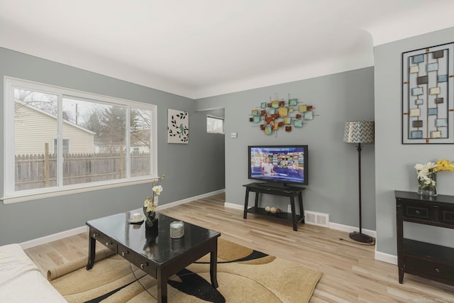 living room with visible vents, baseboards, and wood finished floors