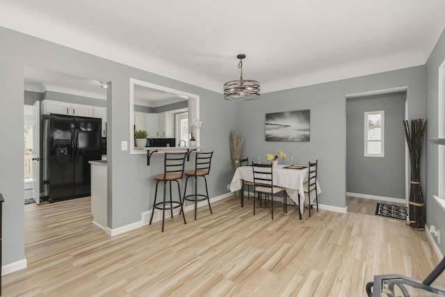 dining space featuring baseboards, an inviting chandelier, and light wood-style floors