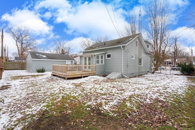 snow covered rear of property featuring an outbuilding, fence, and a deck