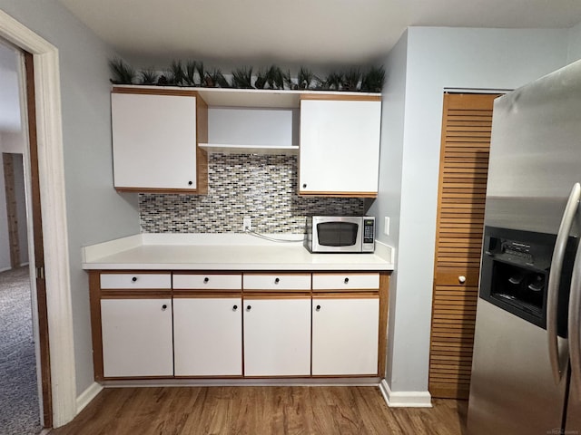 kitchen with backsplash, stainless steel appliances, light countertops, and light wood finished floors