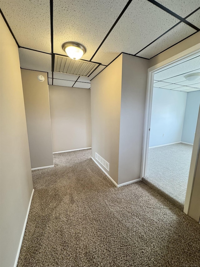 empty room featuring baseboards, carpet, visible vents, and a drop ceiling