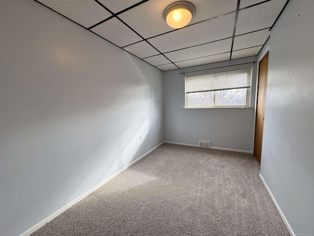 carpeted spare room featuring a paneled ceiling, visible vents, and baseboards