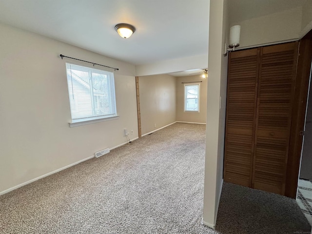 interior space with a closet, carpet, visible vents, and baseboards