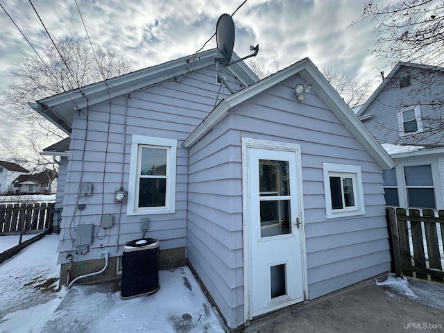 snow covered house featuring fence and central air condition unit