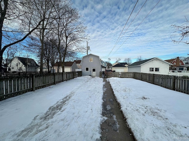 yard layered in snow featuring a fenced backyard and a residential view