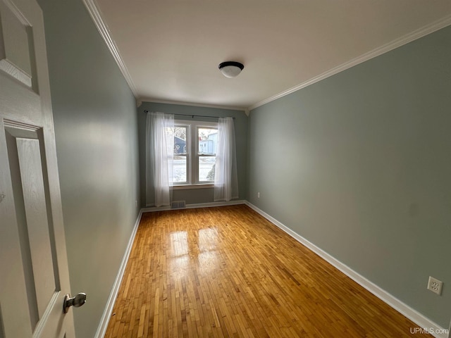 spare room featuring crown molding, wood-type flooring, and baseboards