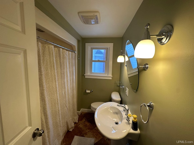 full bathroom featuring a shower with shower curtain, a sink, toilet, and baseboards