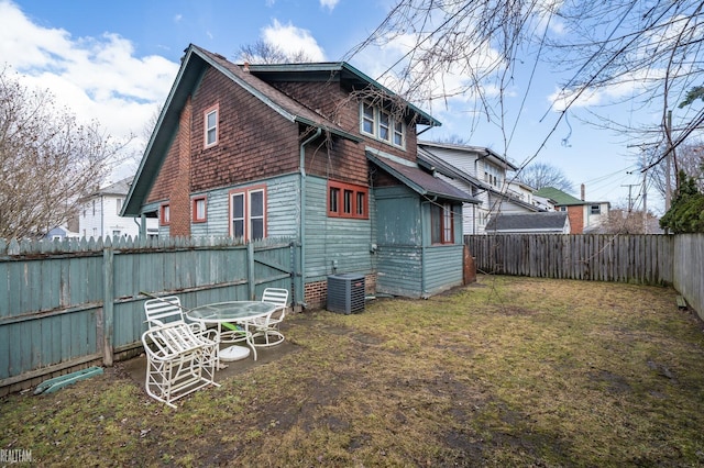 rear view of property with a yard, a shingled roof, a fenced backyard, and central air condition unit