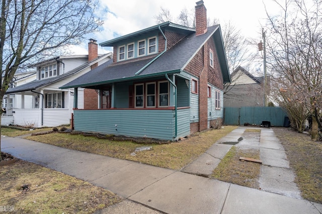 bungalow-style home with driveway, a shingled roof, and a chimney