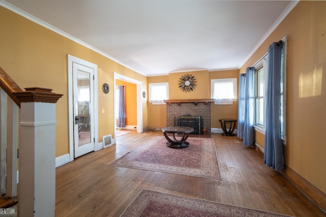 living room featuring ornamental molding, wood-type flooring, visible vents, and a fireplace