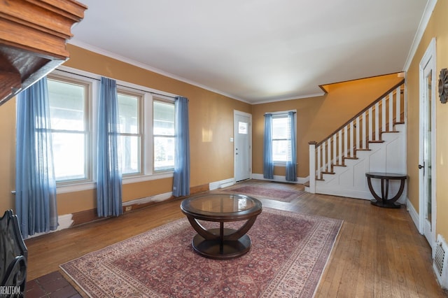 entrance foyer featuring crown molding, stairway, baseboards, and wood finished floors