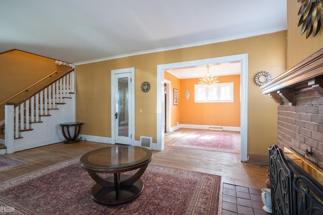 entryway featuring baseboards, visible vents, ornamental molding, wood finished floors, and stairs