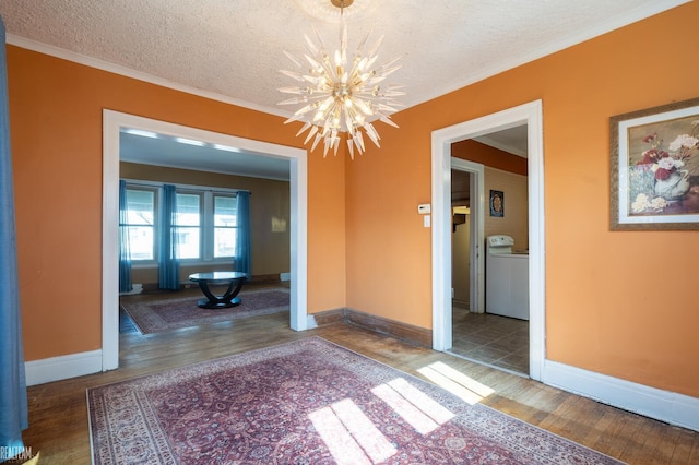 empty room with a chandelier, washer / clothes dryer, a textured ceiling, and wood finished floors