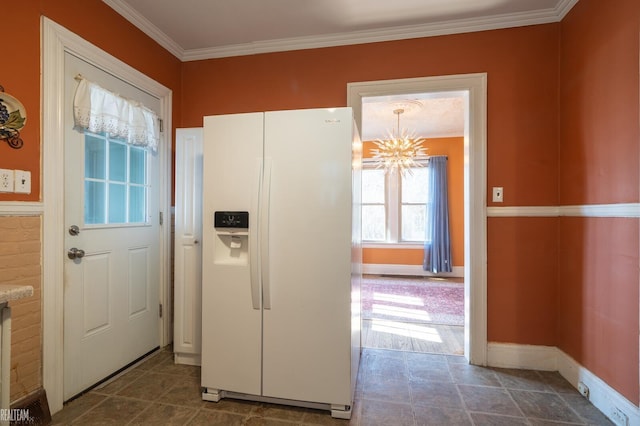 kitchen featuring baseboards, white refrigerator with ice dispenser, ornamental molding, and a chandelier