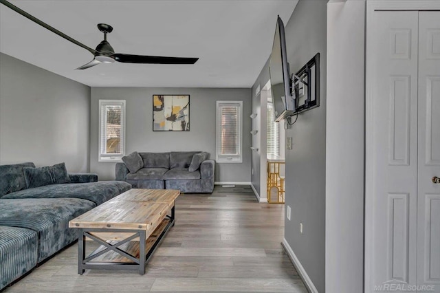 living area with a ceiling fan, baseboards, and wood finished floors