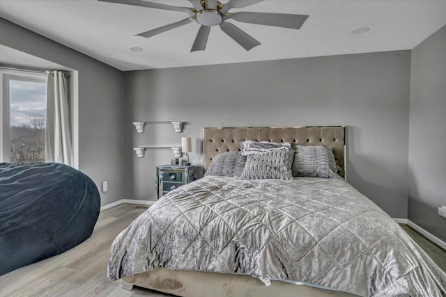 bedroom with wood finished floors, a ceiling fan, and baseboards