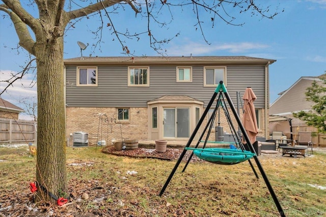 back of house with fence, a lawn, and brick siding