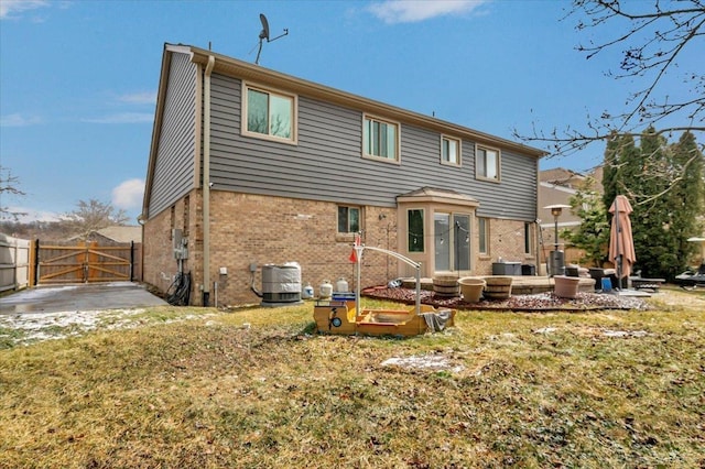 back of house featuring central AC unit, a patio, a gate, fence, and brick siding