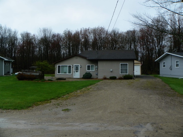 view of front of home featuring a garage, dirt driveway, an outdoor structure, and a front lawn