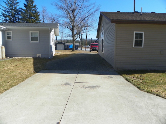 view of side of property featuring concrete driveway and a yard