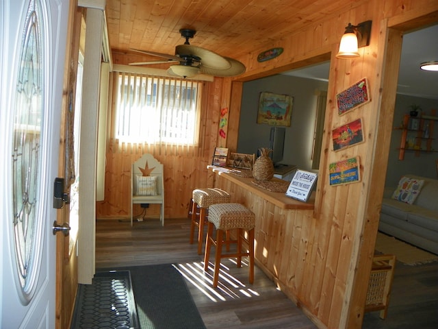 bar featuring wooden ceiling, wood finished floors, a ceiling fan, and wooden walls