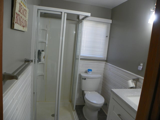 full bathroom featuring wainscoting, a shower stall, toilet, and vanity