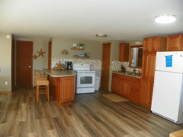 kitchen with decorative backsplash, brown cabinetry, a sink, wood finished floors, and white appliances