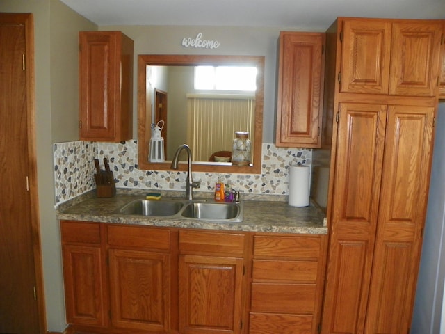 kitchen featuring decorative backsplash, brown cabinetry, and a sink