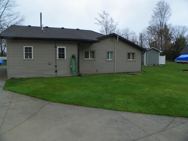 back of property with a shingled roof and a lawn