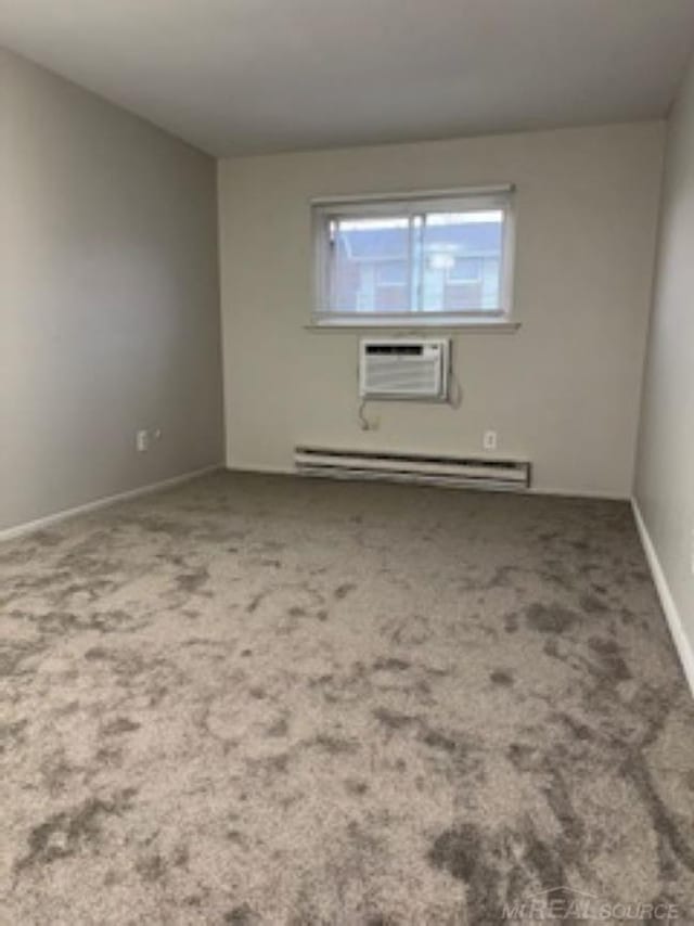 carpeted spare room featuring an AC wall unit, a baseboard radiator, and baseboards