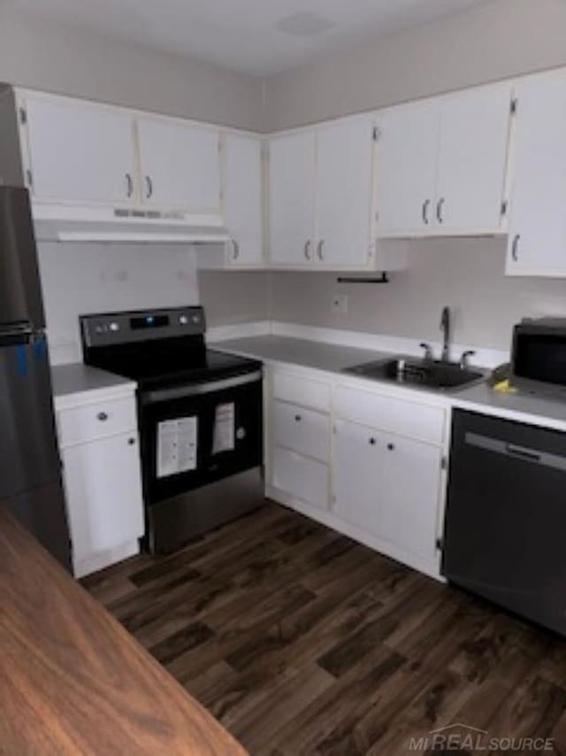 kitchen featuring white cabinets, dark wood finished floors, appliances with stainless steel finishes, under cabinet range hood, and a sink