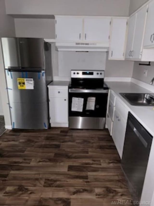 kitchen with stainless steel appliances, light countertops, white cabinetry, a sink, and under cabinet range hood