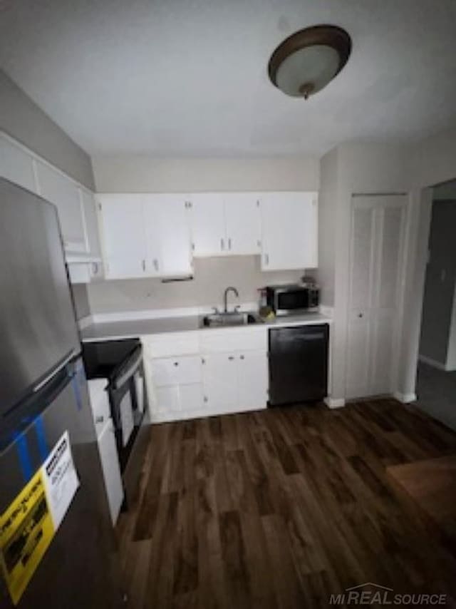 kitchen featuring dark wood finished floors, white cabinets, appliances with stainless steel finishes, light countertops, and a sink